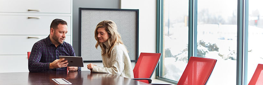 A man and woman collaborating in a conference room with modern red chairs