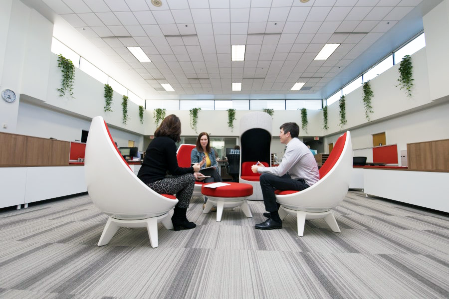 Three people sitting on modern white and red Sway Lounge chairs having a discussion